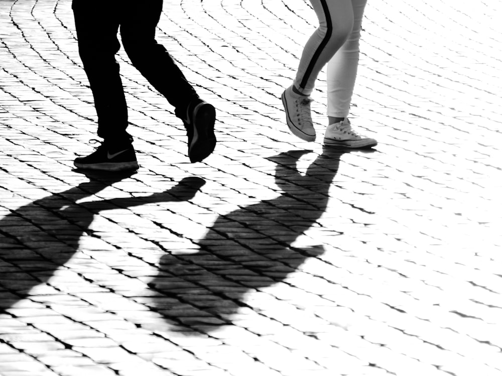 grayscale photography of two person walking on brick road