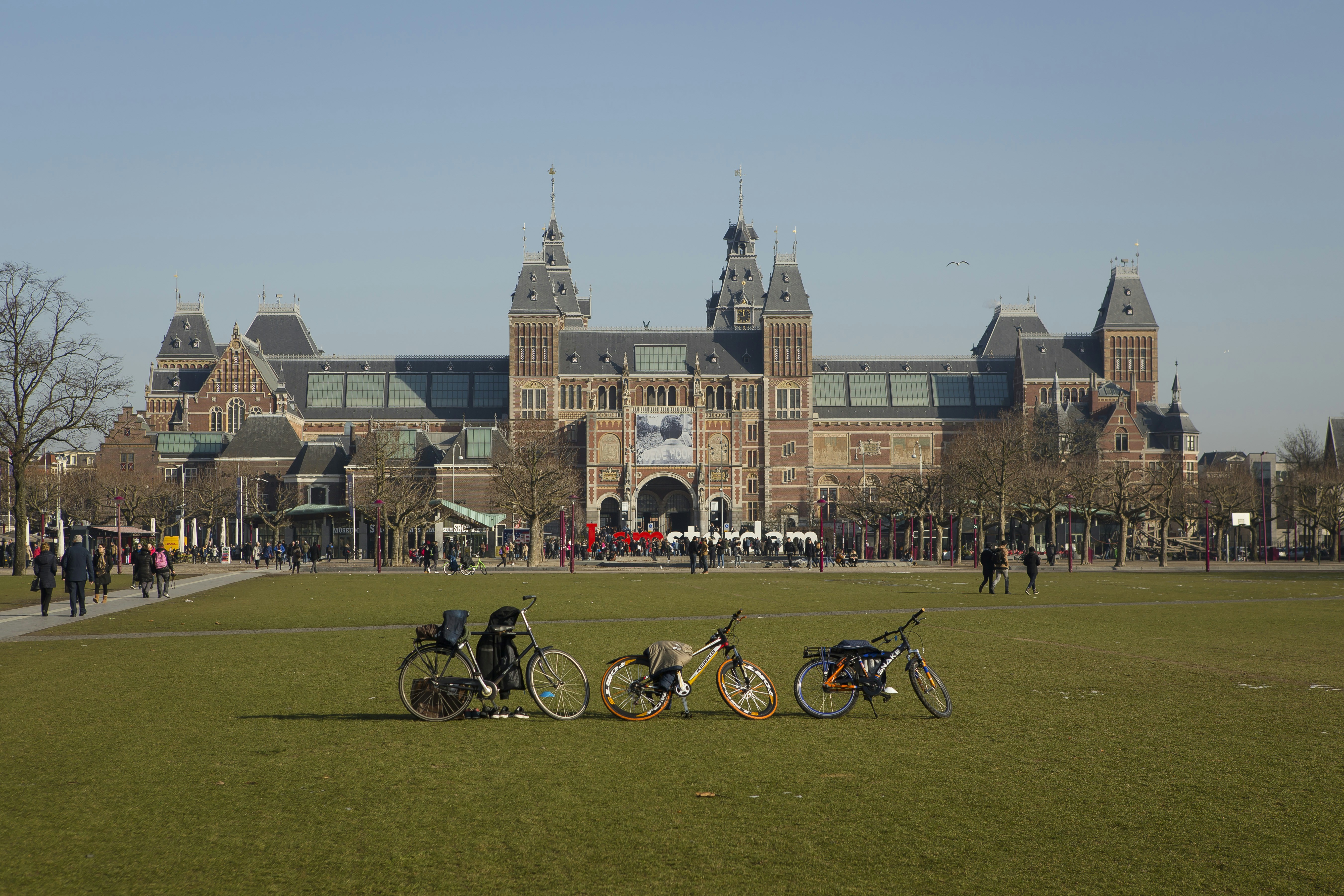 personnes marchant près du Rijksmuseum à Amsterdam sous un ciel bleu et blanc pendant la journée