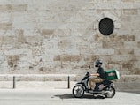 man driving motor scooter delivering good