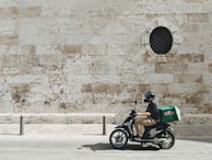 man driving motor scooter delivering good