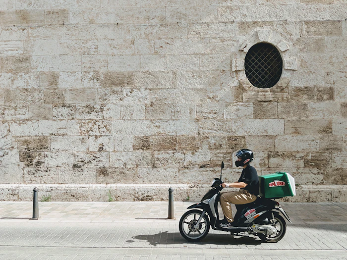 Motorizado de delivery con caja verde recorriendo la ciudad
