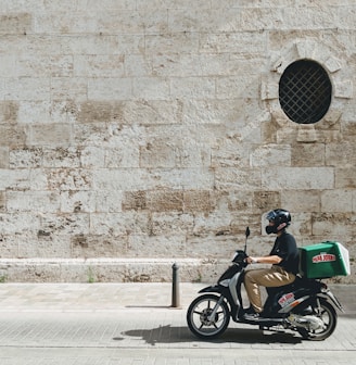 man driving motor scooter delivering good