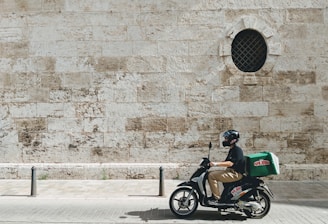 man driving motor scooter delivering good