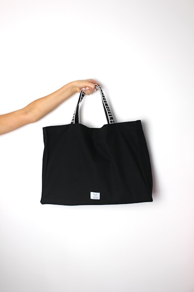 Black canvas tote bag on a white background — photo by He's Her Lobster on Unsplash