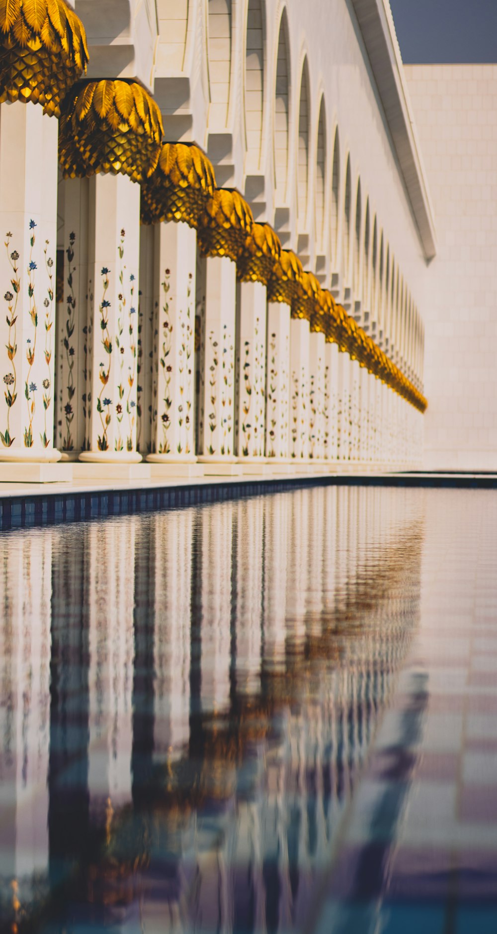 gold and white building pillars near body of water