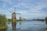 Scenic view of the Zaanse Schans windmills with a calm river in the foreground under a bright sky.