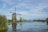 Scenic view of the Zaanse Schans windmills with a calm river in the foreground under a bright sky.