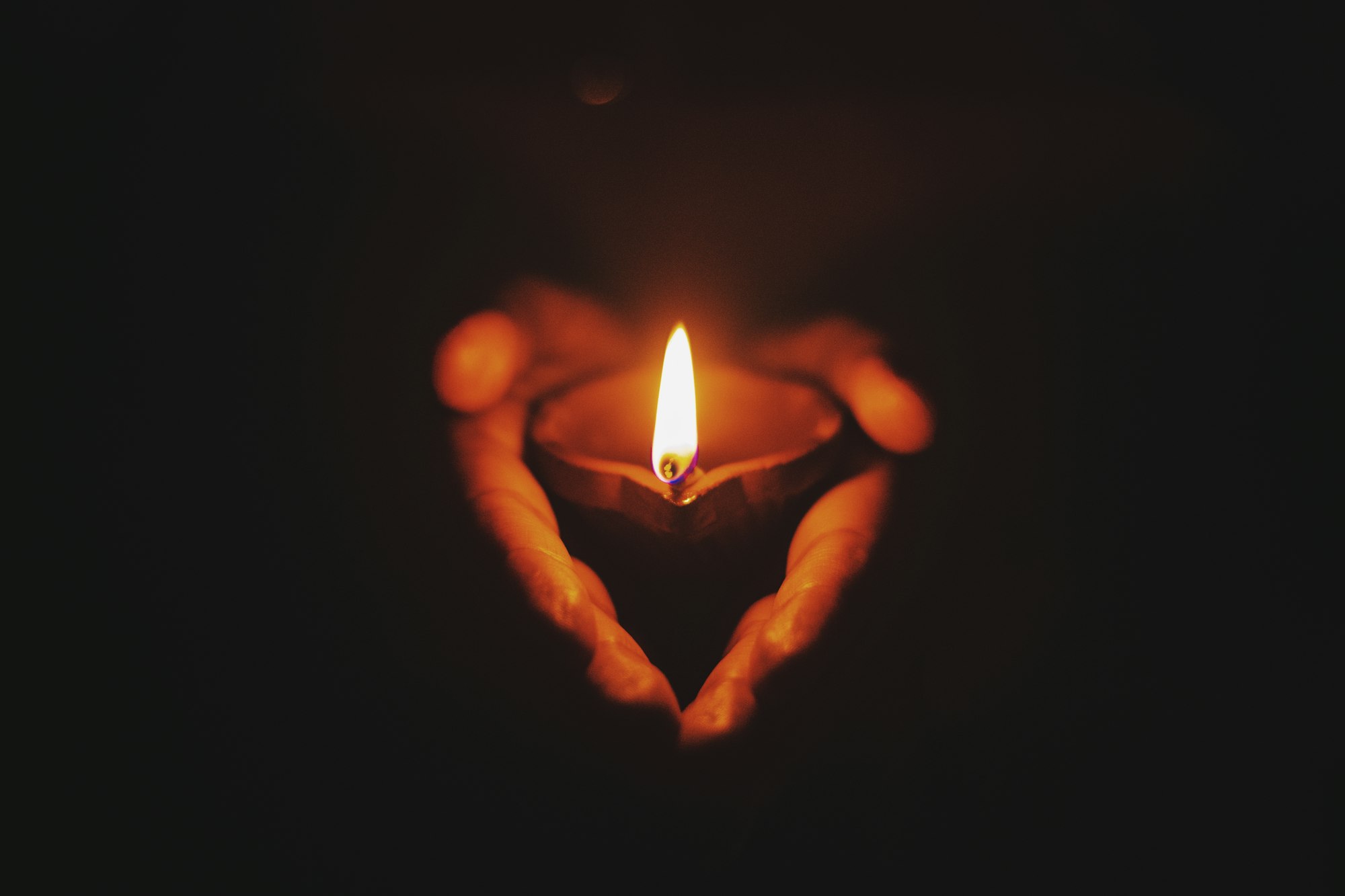 A candle hold by hands in the dark