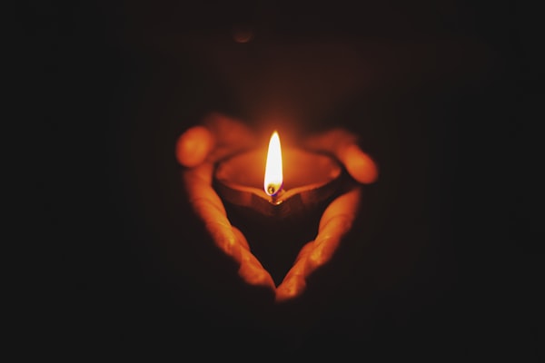 A candle hold by hands in the dark