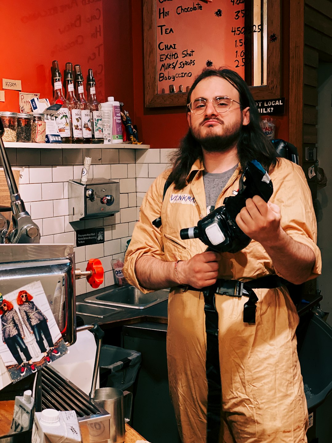 man holding black camera and wearing yellow jumpsuit