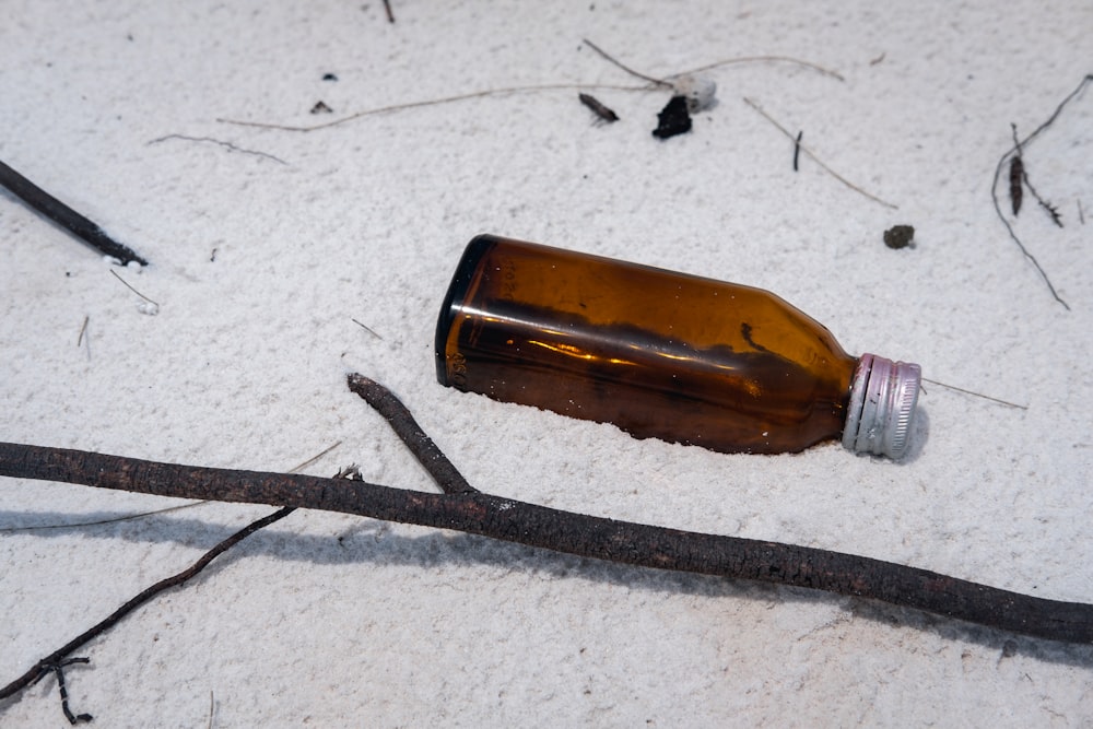 Bouteille en verre ambré à côté de bois flotté