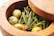 Elegant jar of infused herbal olive oil surrounded by fresh herbs and olives.
