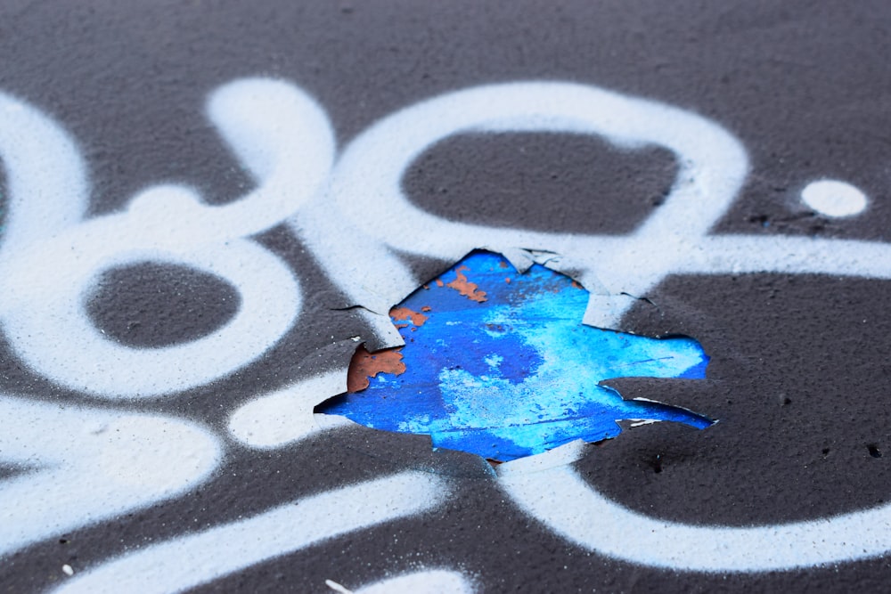 a piece of blue paint sitting on top of a sidewalk