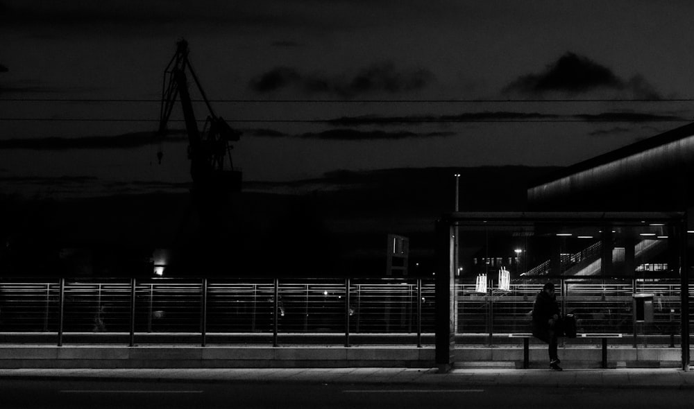 grayscale photography of person sitting on train station