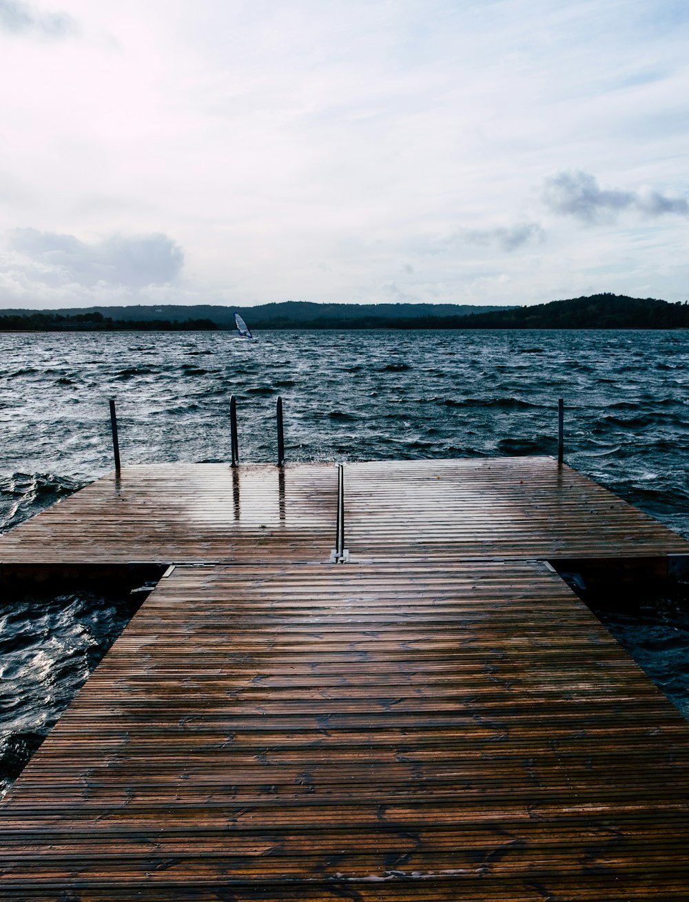 brown wooden dock viewing blue sea and mountain under white and blue sky during daytime