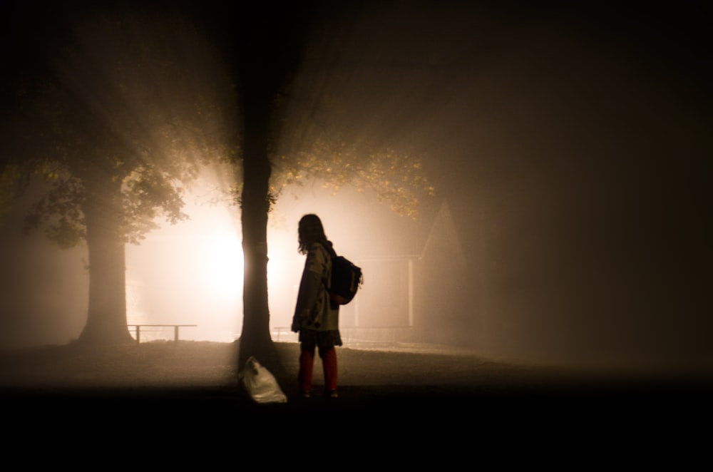 Frau steht neben Baum mit Lichtstrahl