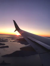 Image of a scenic airplane window view over tropical beaches during sunset.