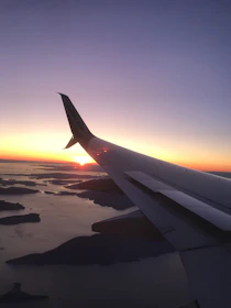 Image of a scenic airplane window view over tropical beaches during sunset.