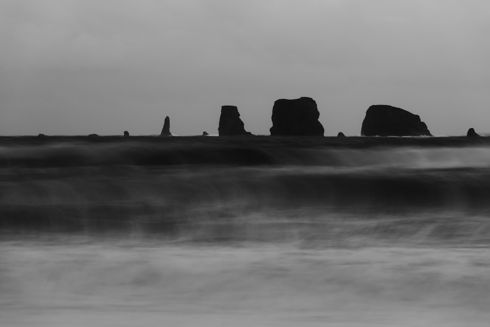 a black and white photo of rocks in the ocean