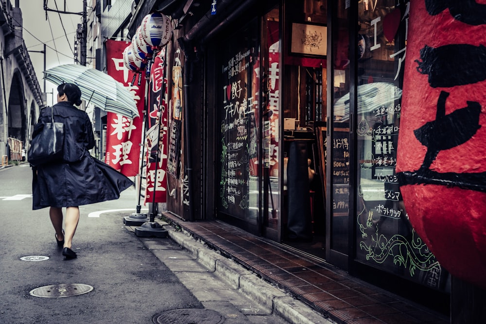 red umbrella on sidewalk near store front during daytime