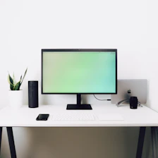 A clean, bright workspace with a laptop and smart gadgets neatly arranged on a white desk.