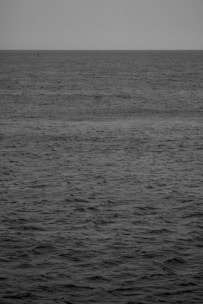 Minimalist black and white image of a camera lens reflecting the horizon over the ocean.