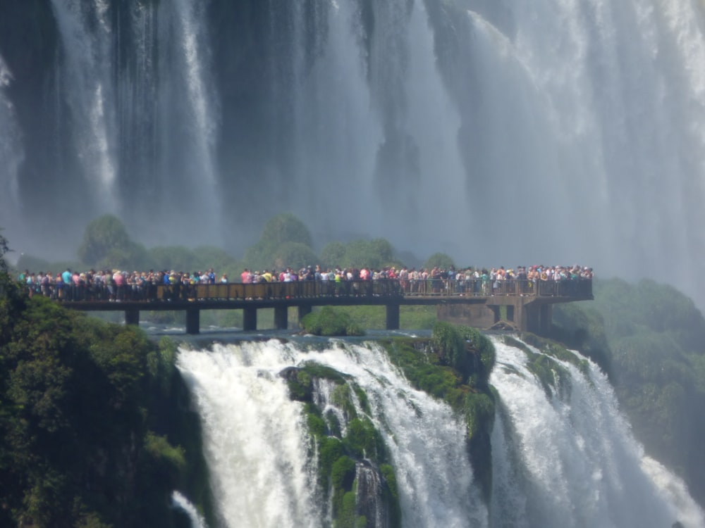 a group of people standing on a bridge over a waterfall
