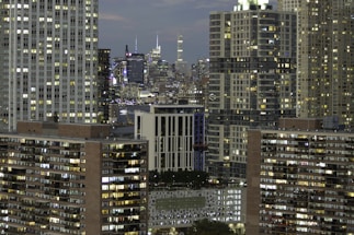 A vibrant NYC skyline featuring apartment buildings glowing at dusk.