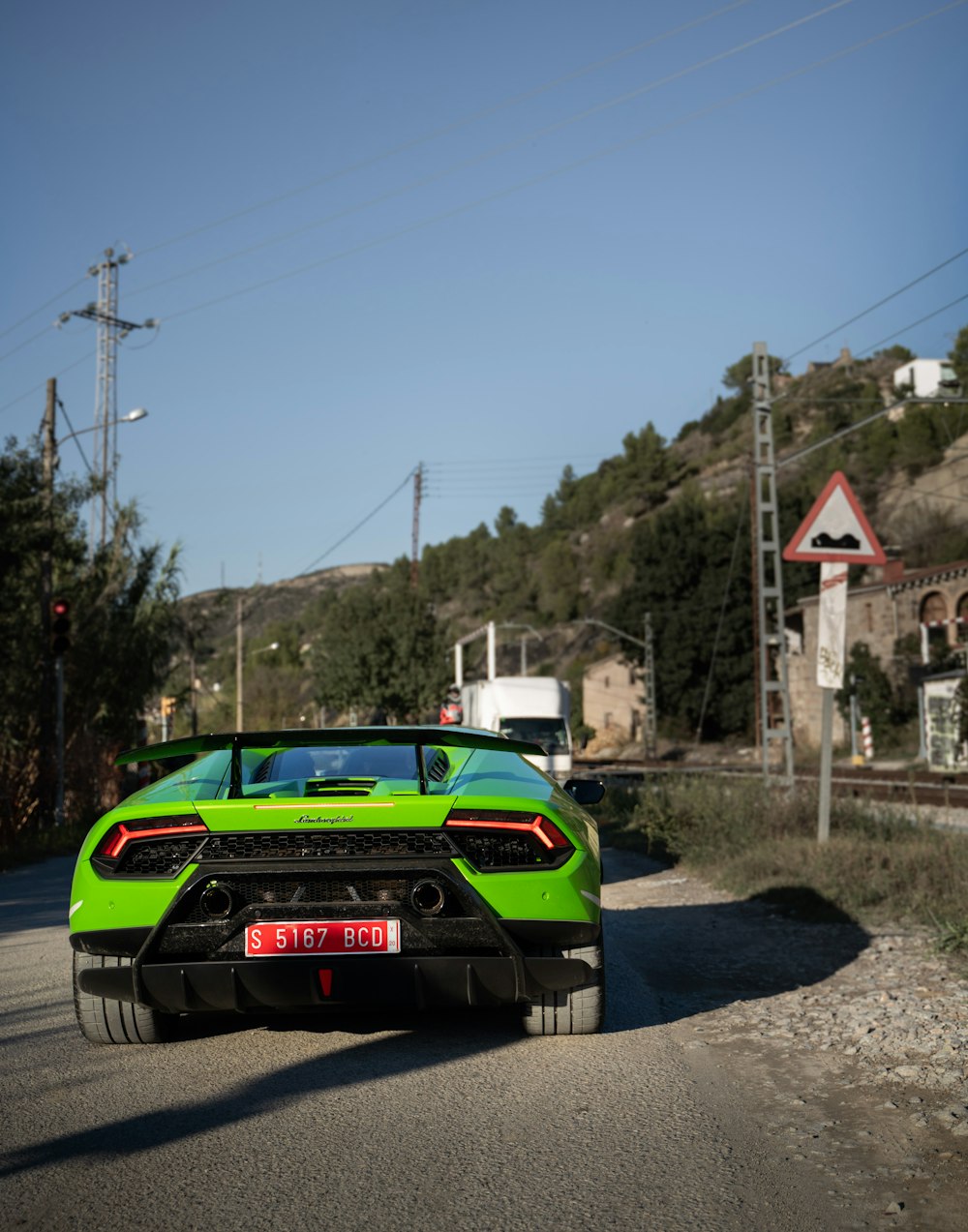 green car on road near buildings and trees during day