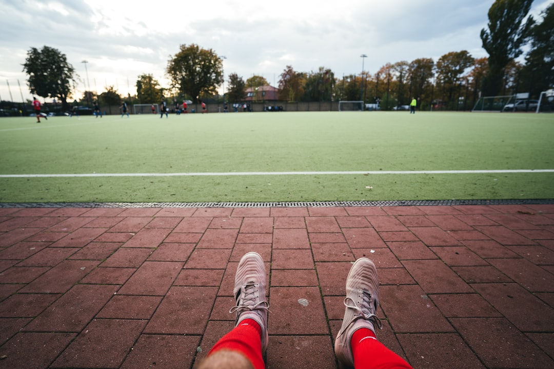 man sits in front soccer field at daytime