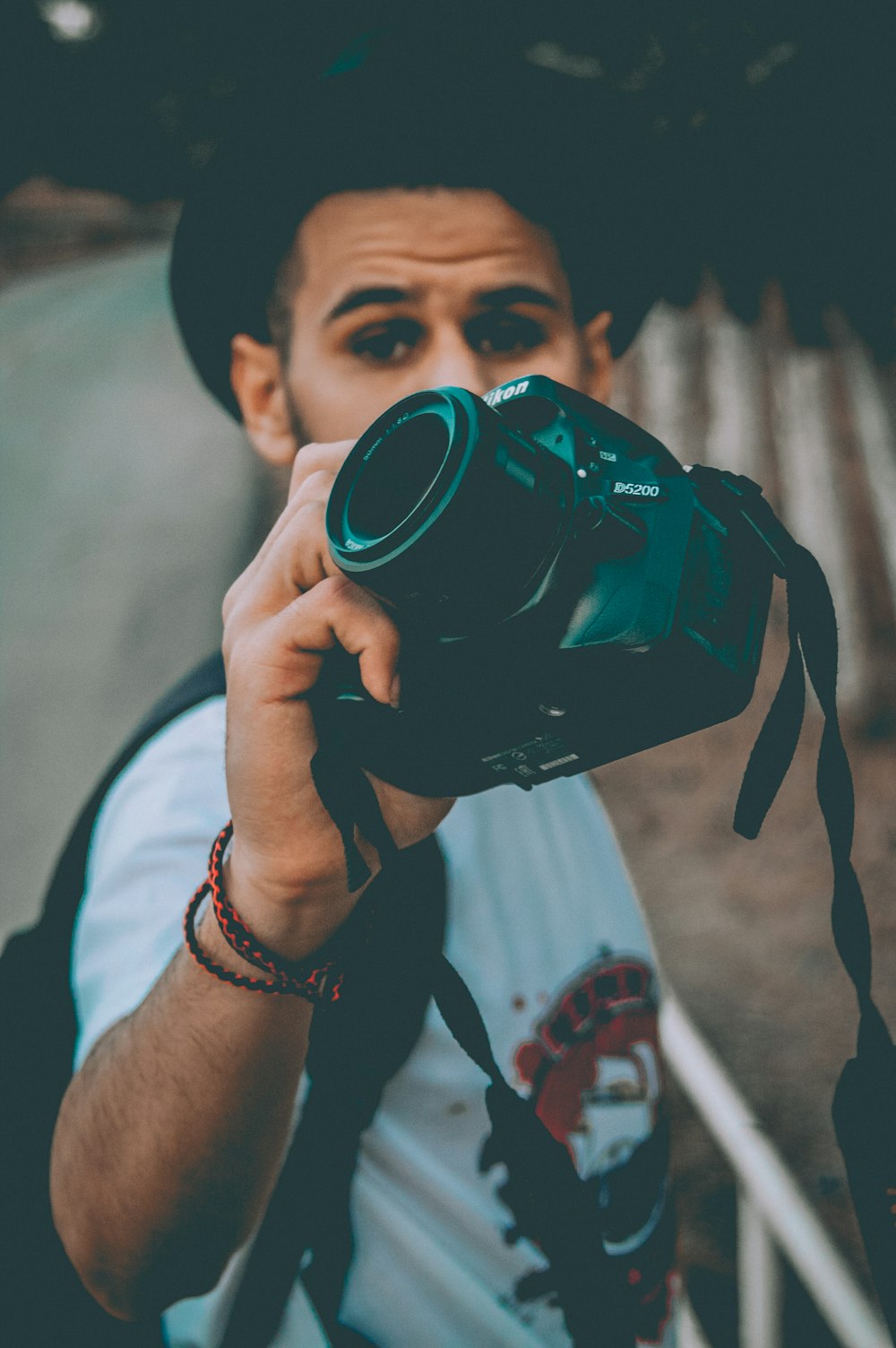 man wearing white and black printed crew-neck t-shirt standing while holding DSLR camera