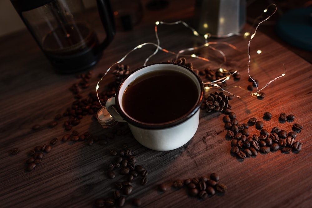 coffee filled mug on wooden surface beside coffee beans