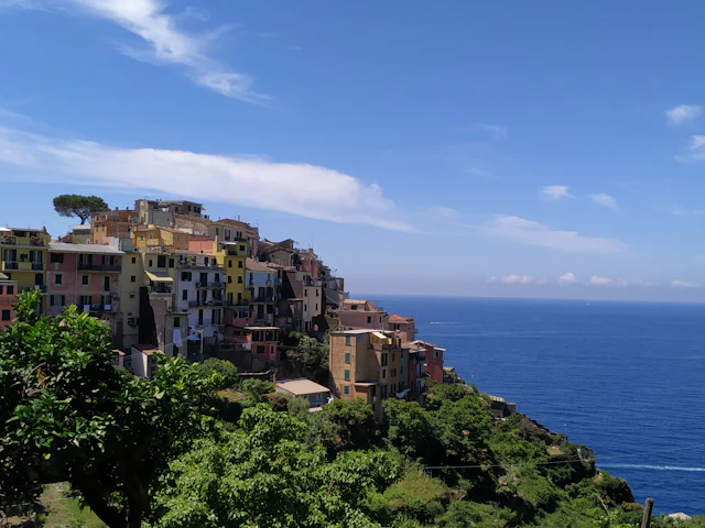 Corniglia's houses perched on its cliff-top promontory above the sea under a clear blue sky