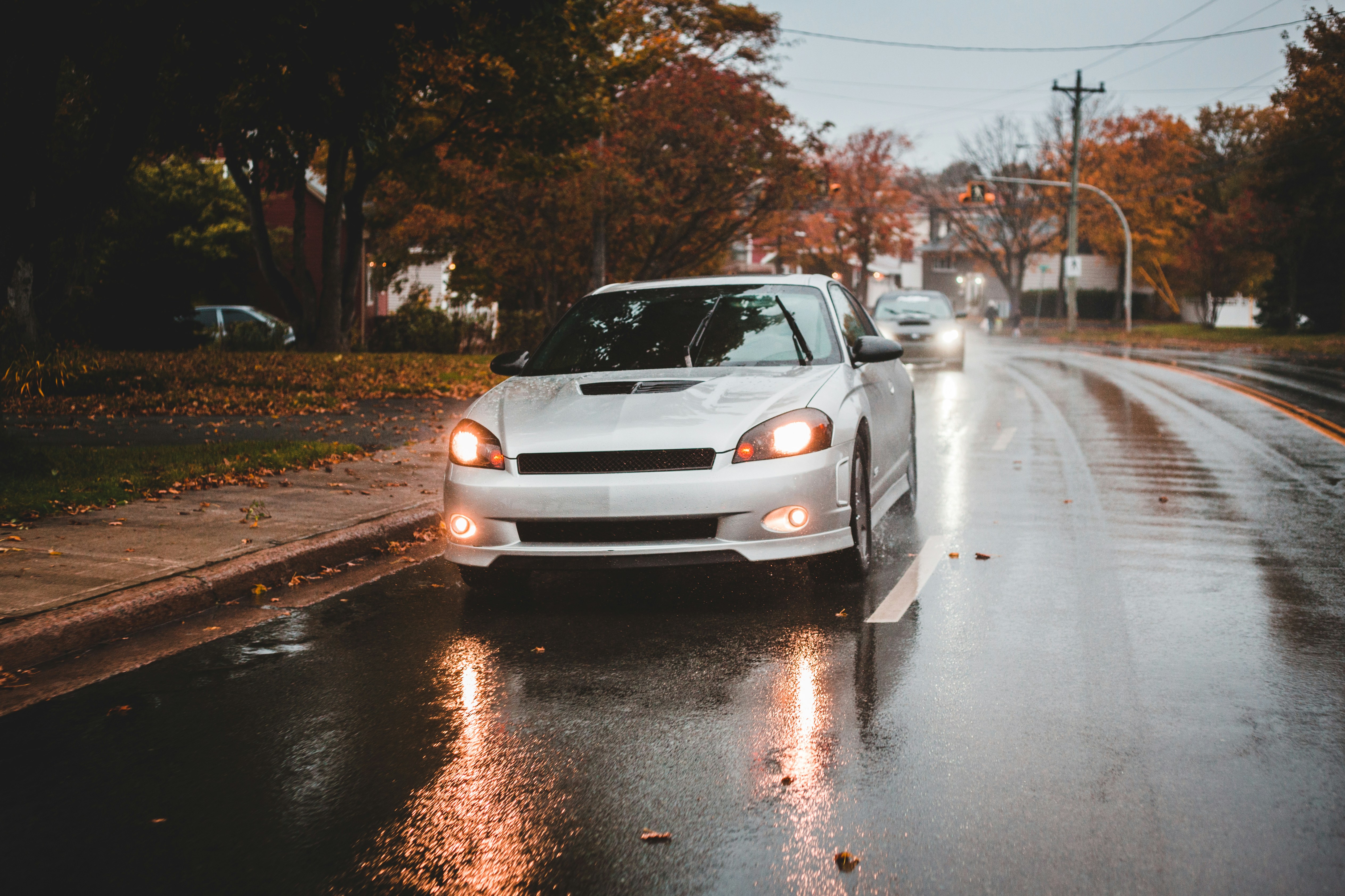 Small inexpensive compact car driving through a city street at sunset