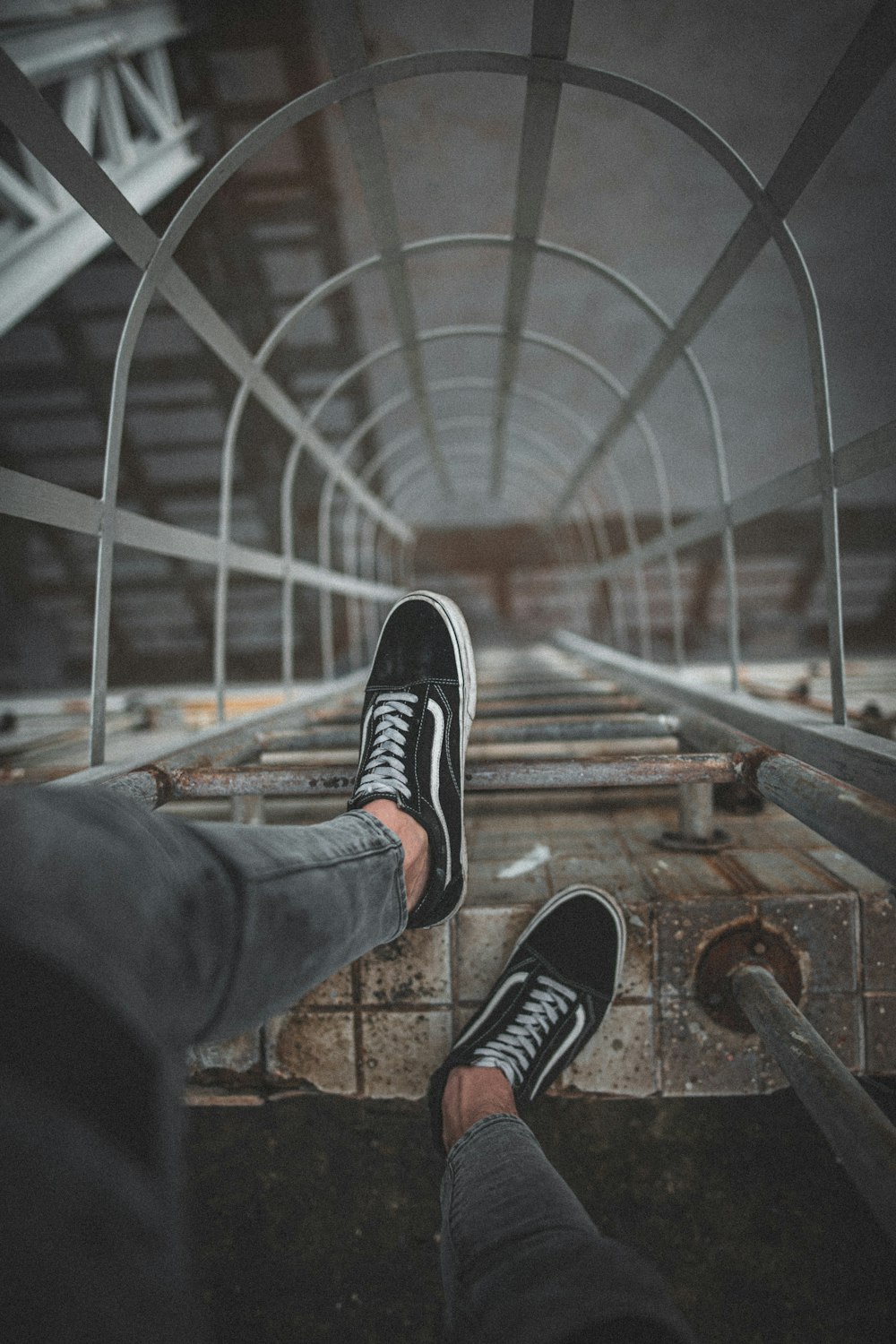 man wears black Vans low-top sneakers on top of wall ladder