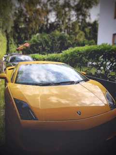 A shiny sports car parked outdoors, freshly detailed with water droplets glistening in the sun.