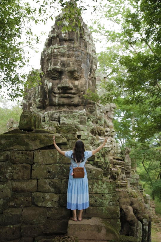 woman in blue dress standing on concrete slab beside statue in Siem Reap Cambodia