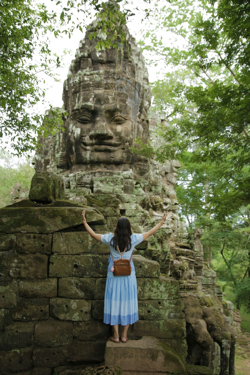 woman in blue dress standing on concrete slab beside statue