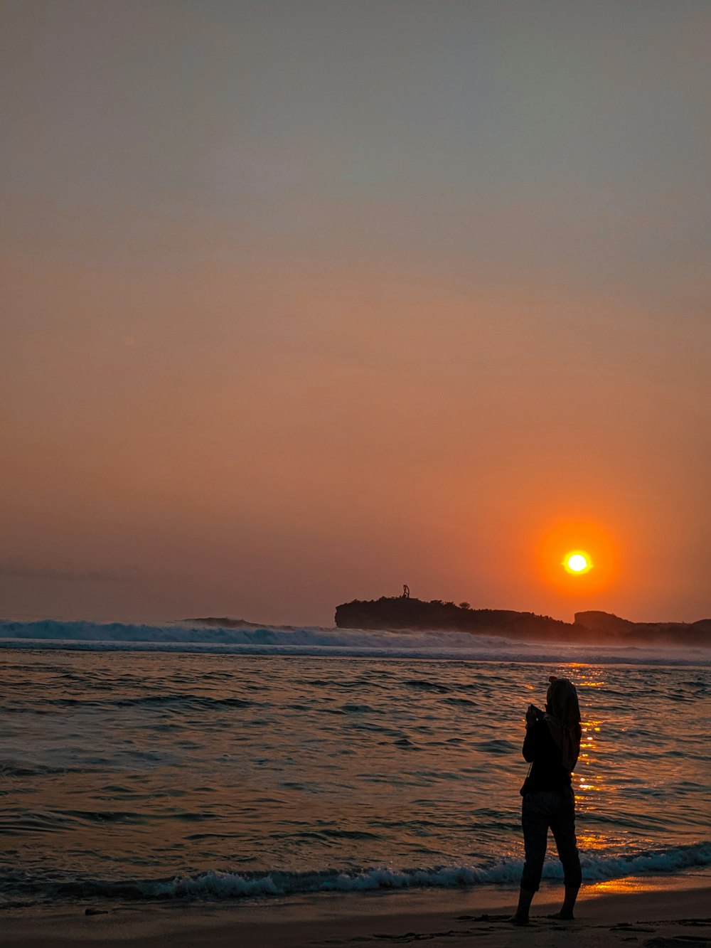 person standing on seashore during sunset