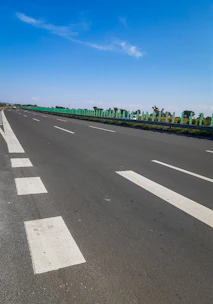 A close-up photo of a clean, well-maintained road with clear markings under a bright sky.