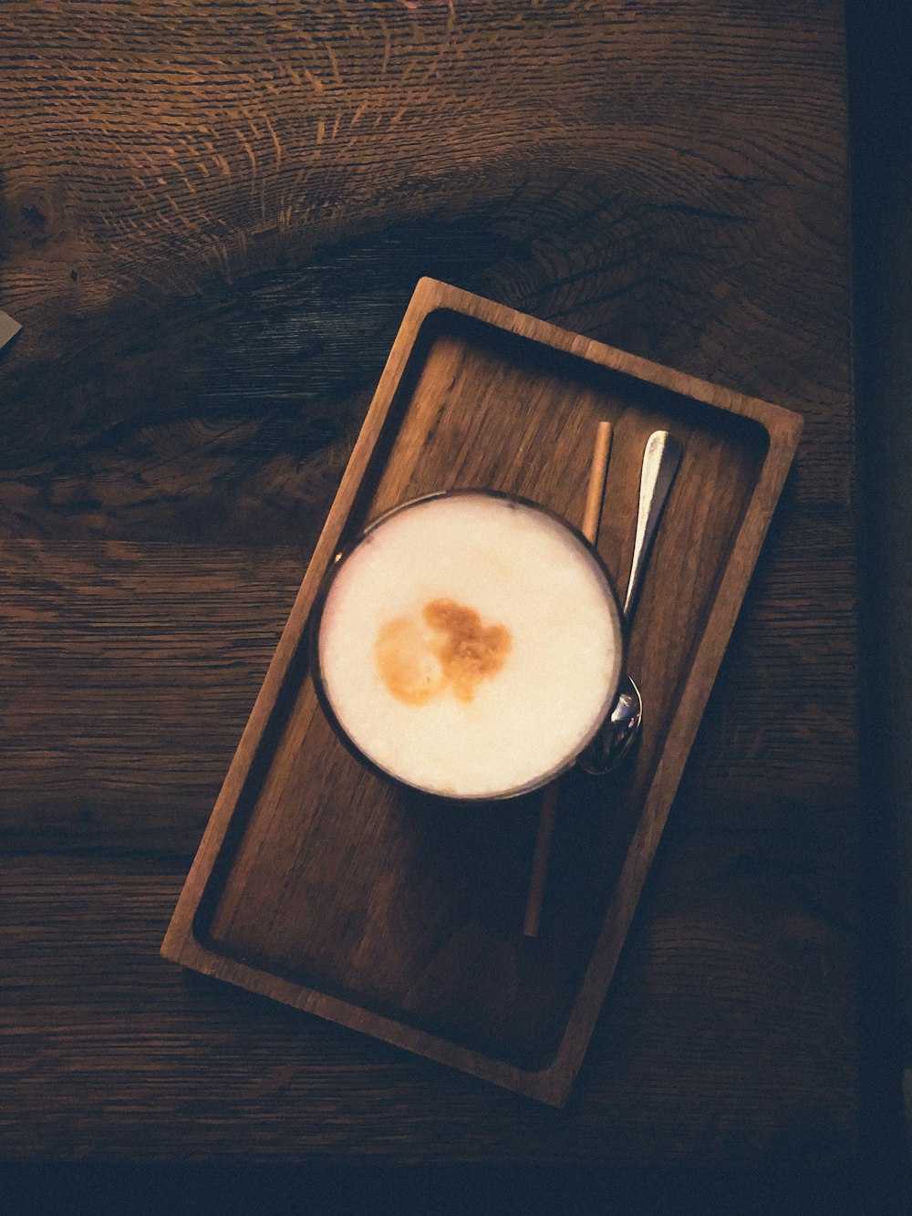 cappuccino in clear glass near gray stainless steel spoon