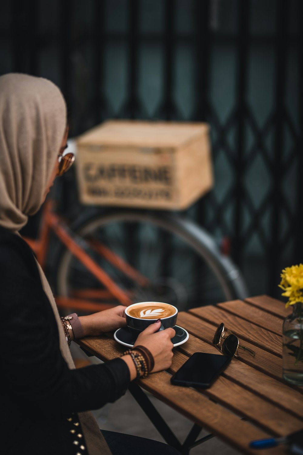 woman sitting beside wooden table holding black mug