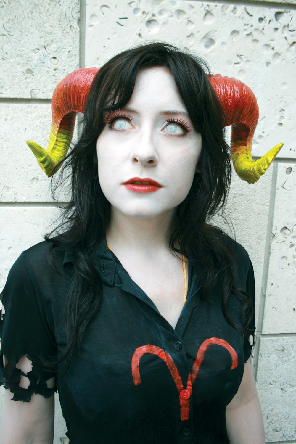 woman wearing black and red blouse and red and yellow horn standing