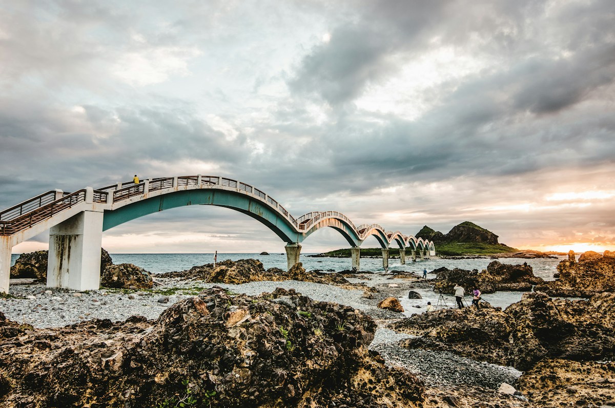 台東成功鎮三仙台的八拱跨海步橋，連接本島與離岸小島，前景是礁岩與礫石灘