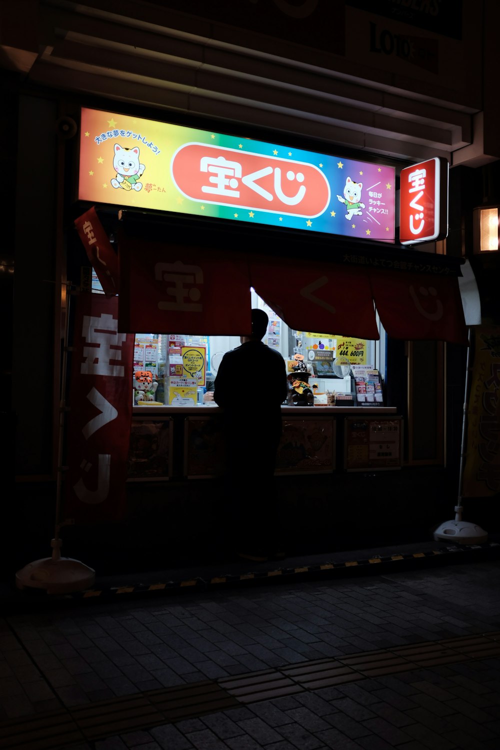 man standing in front of store at nighttime
