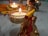 A beautifully decorated small figurine is holding a lit tealight candle. Around the figure, there are more delicate decorations and intricate patterns, including marigold flowers set on a colorful background. The ambiance is festive, warm, and inviting.