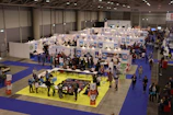 Wide shot of a vibrant, well-lit exhibition area showcasing multiple stands designed by the company.