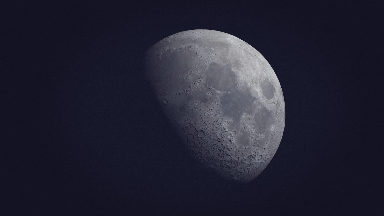 Near first quarter, sunlight rakes across the terminator, so craters along the shadow line cast shadows and show depth.
