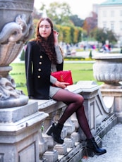 woman sitting on grey concrete bench wearing black coat during daytime