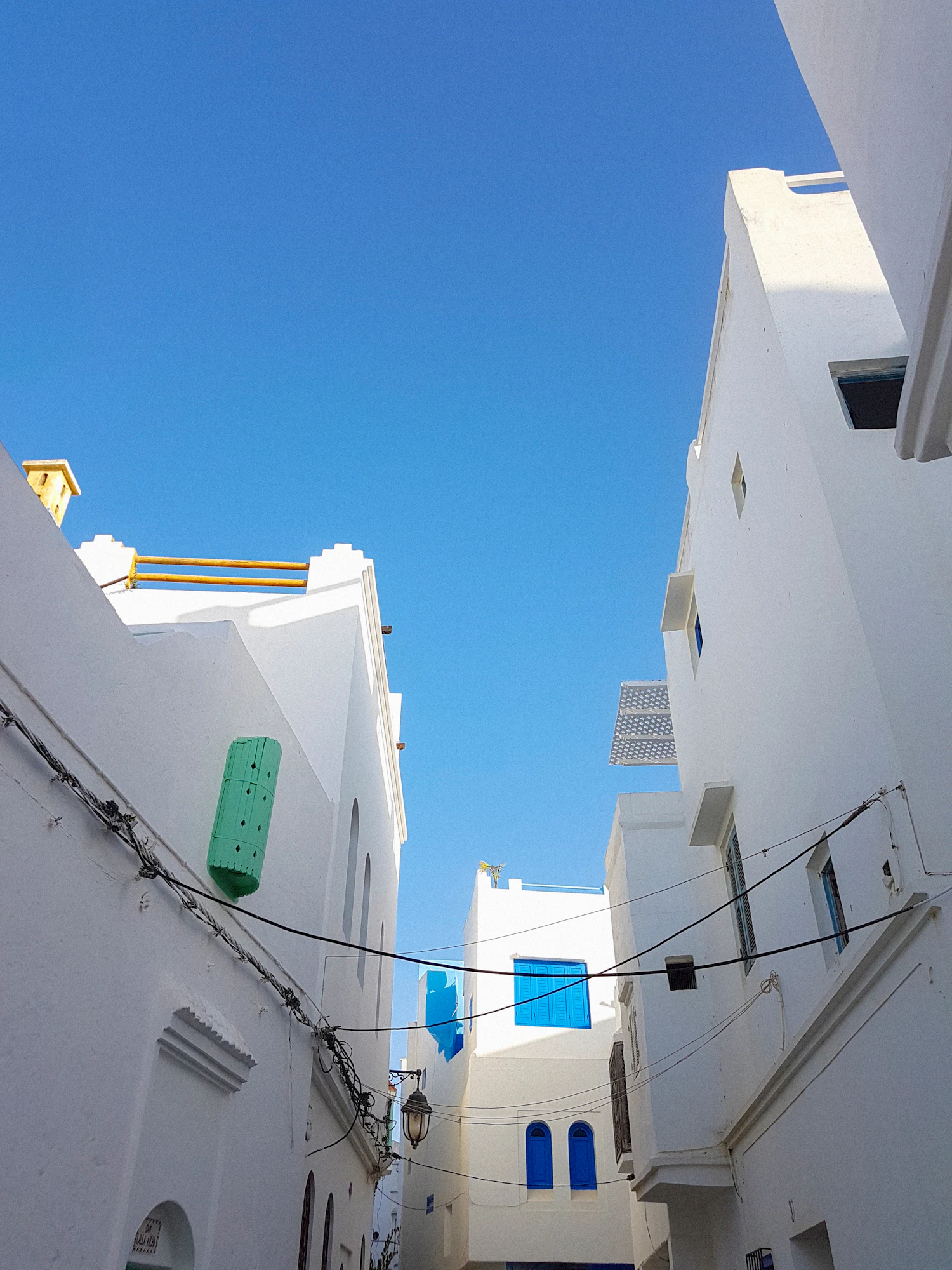 A whitewashed lane in the Asilah medina under a clear blue sky